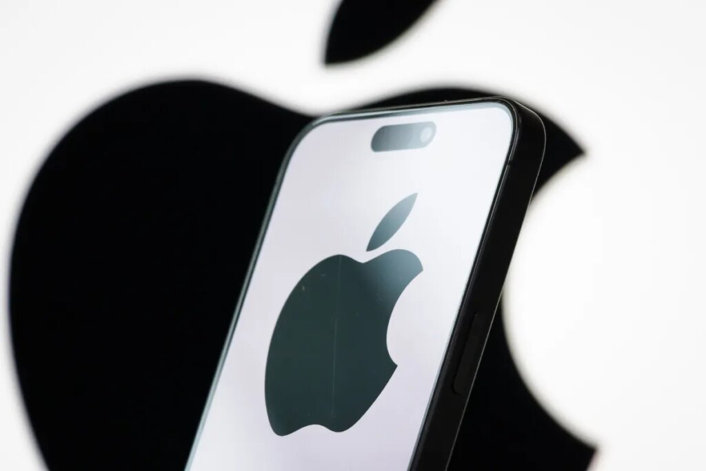 In this photo illustration, the logo of Apple Inc. is displayed on a smartphone screen, with the company's iconic black apple symbol visible in the background.