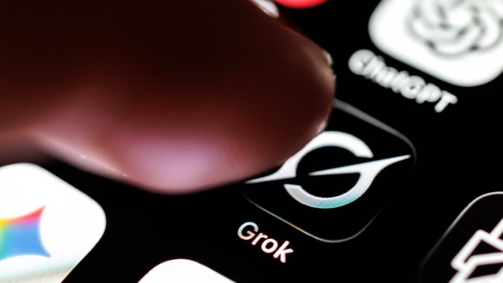 A person's finger hovering over the Grok app icon on a phone screen.