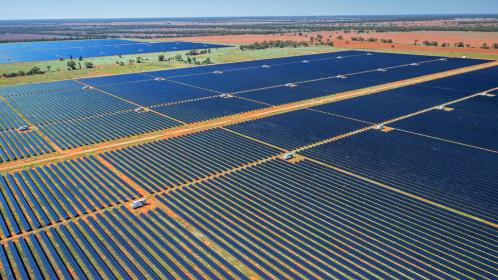 image of a red, dusty scrubland covered in row after row of photovoltaic panels.