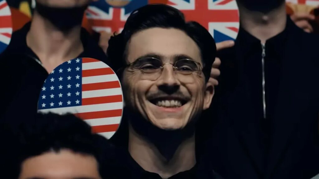 Timothée Chalamet smiles and holds a ping pong paddle in Marty Supreme